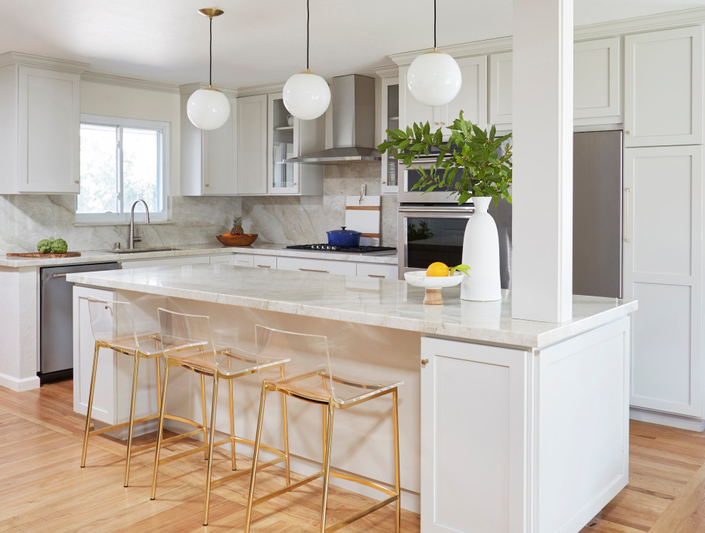 Inredning av ett klassiskt mellanstort grå grått kök, med en enkel diskho, skåp i shakerstil, grå skåp, bänkskiva i kvartsit, grått stänkskydd, stänkskydd i sten, rostfria vitvaror, mellanmörkt trägolv, en köksö och brunt golv