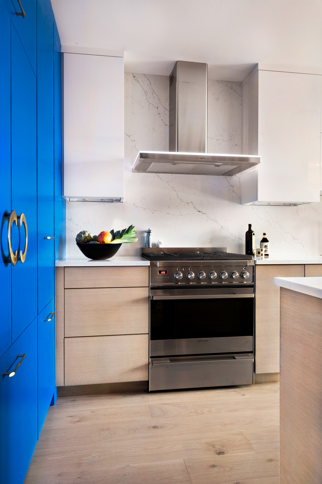 Inspiration för mellanstora moderna vitt kök, med en undermonterad diskho, släta luckor, blå skåp, bänkskiva i kvarts, vitt stänkskydd, stänkskydd i sten, rostfria vitvaror, mellanmörkt trägolv, en köksö och brunt golv