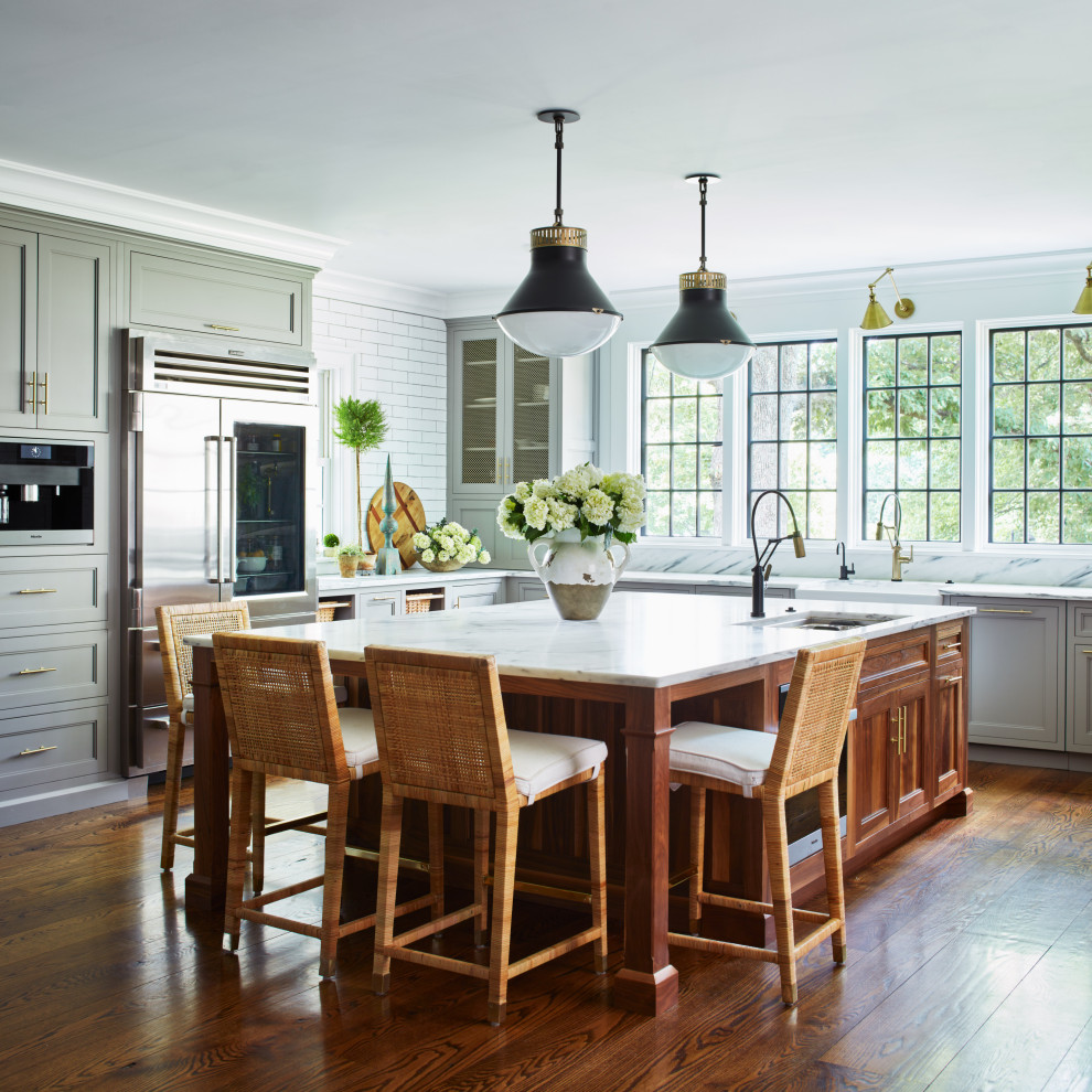 Kitchen - large cottage u-shaped medium tone wood floor and brown floor kitchen idea in New York with an undermount sink, recessed-panel cabinets, gray cabinets, marble countertops, white backsplash, ceramic backsplash, stainless steel appliances, an island and white countertops