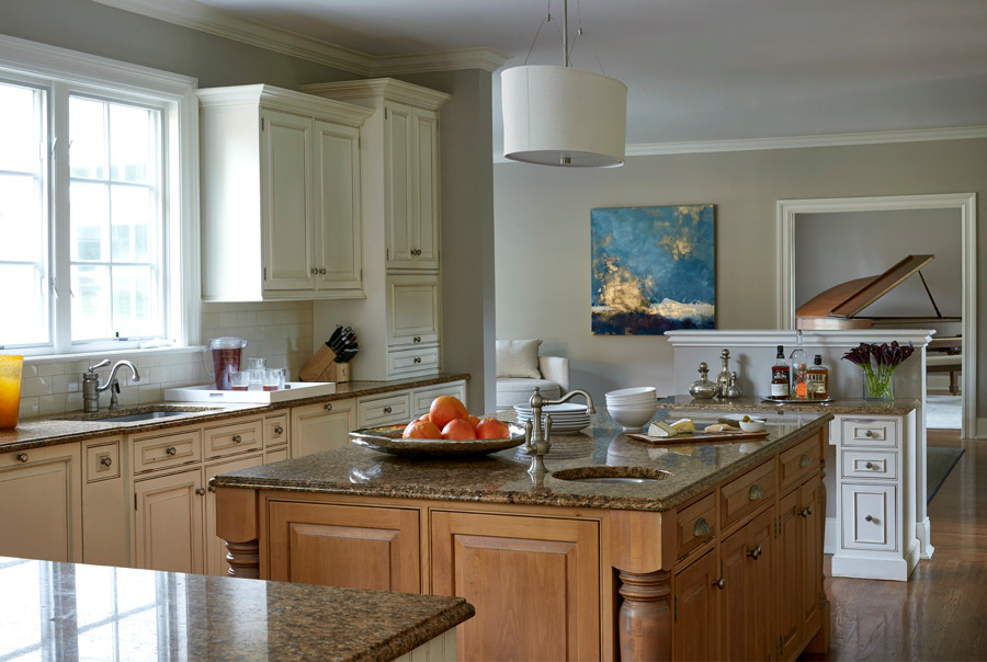 Inredning av ett klassiskt stort kök, med en enkel diskho, luckor med upphöjd panel, vita skåp, granitbänkskiva, beige stänkskydd, stänkskydd i keramik, rostfria vitvaror, mellanmörkt trägolv och en köksö
