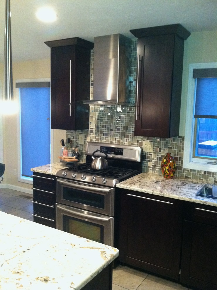 Foto på ett mellanstort funkis kök, med en integrerad diskho, släta luckor, skåp i mörkt trä, granitbänkskiva, flerfärgad stänkskydd, glaspanel som stänkskydd, rostfria vitvaror och en köksö