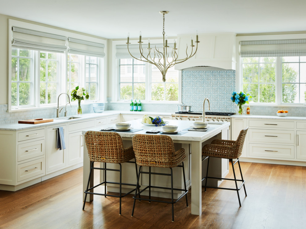 Inredning av ett klassiskt mycket stort grå grått u-kök, med en undermonterad diskho, skåp i shakerstil, vita skåp, blått stänkskydd, rostfria vitvaror, mellanmörkt trägolv, en köksö och brunt golv