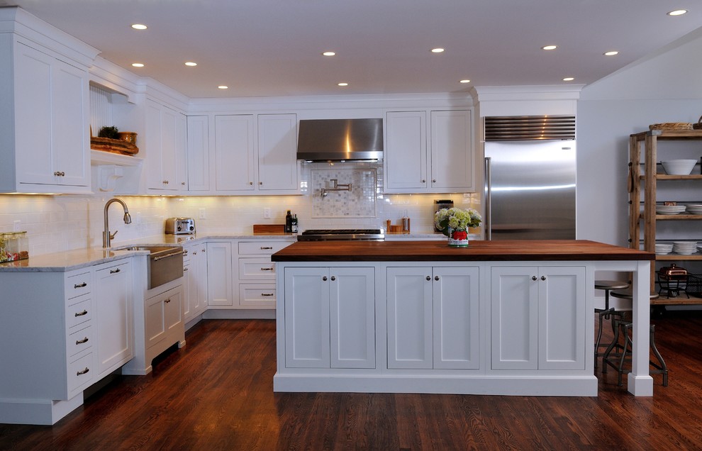 Inspiration for a large transitional l-shaped dark wood floor open concept kitchen remodel in New York with shaker cabinets, white cabinets, subway tile backsplash, stainless steel appliances, a farmhouse sink, marble countertops, yellow backsplash and an island