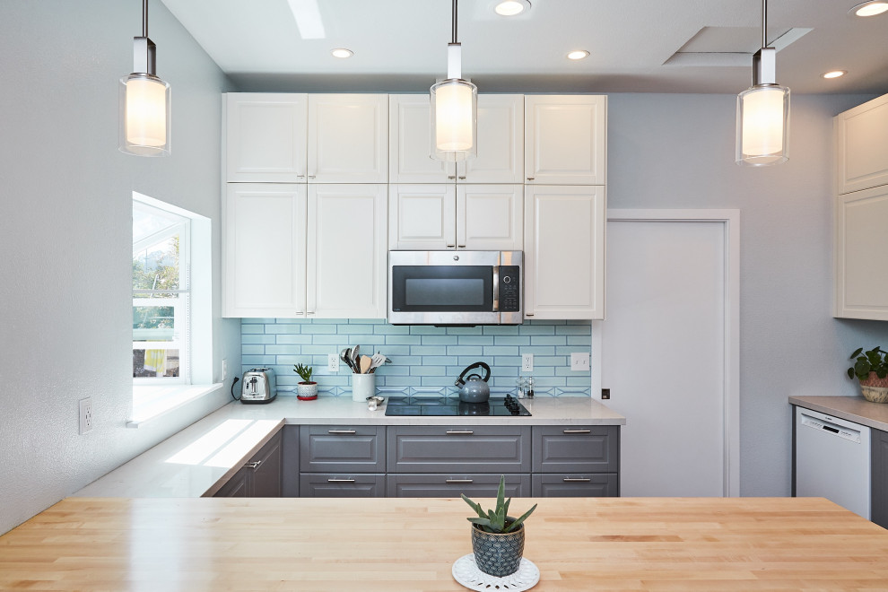 Mid-sized transitional u-shaped bamboo floor and brown floor eat-in kitchen photo in Other with raised-panel cabinets, gray cabinets, blue backsplash, subway tile backsplash, a peninsula, an undermount sink, wood countertops, stainless steel appliances and white countertops