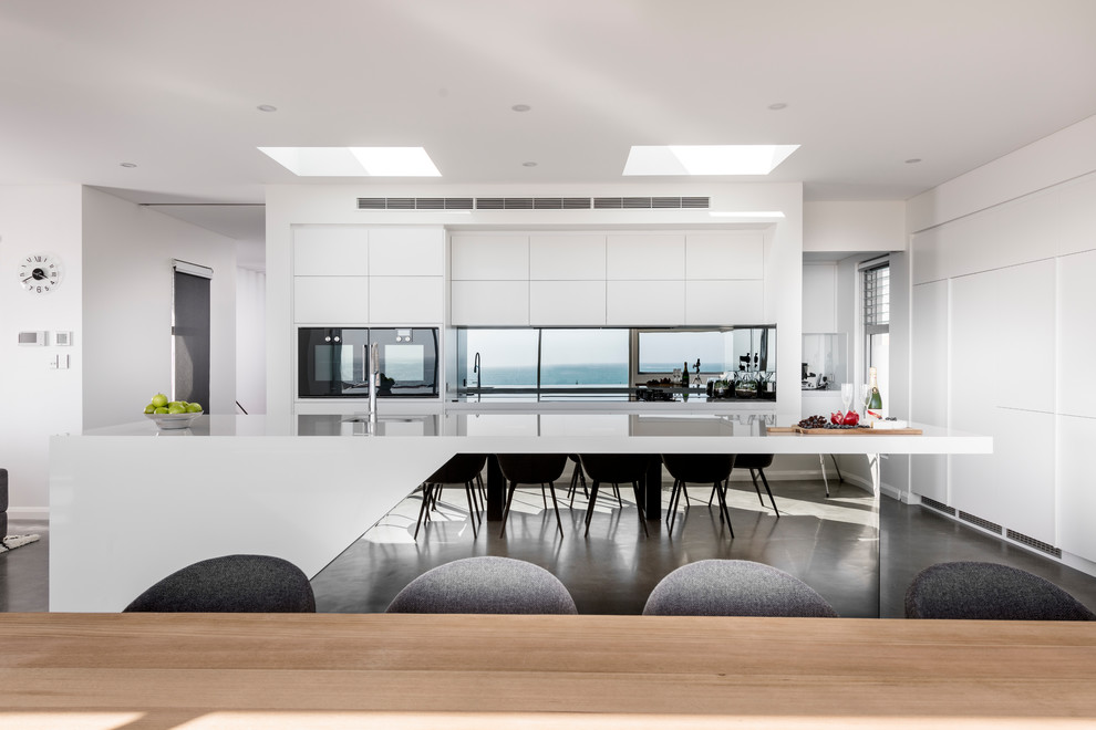 Idee per una grande cucina ad ambiente unico minimalista con top in superficie solida, paraspruzzi a specchio, pavimento in cemento e pavimento grigio