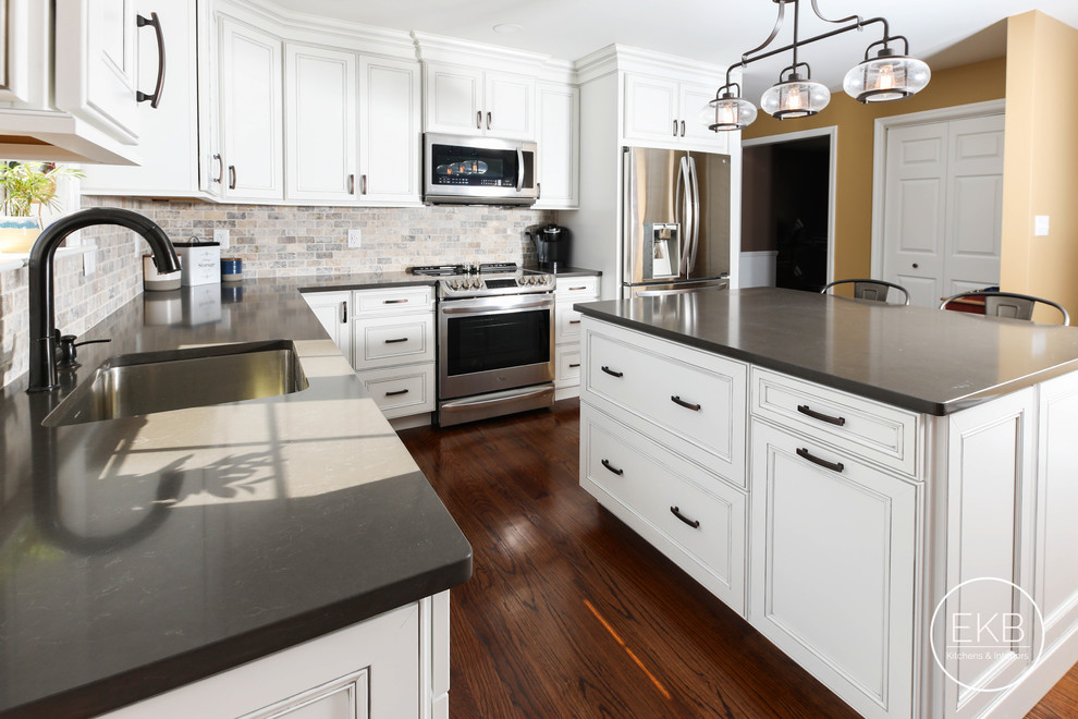 Example of a mid-sized classic l-shaped dark wood floor and brown floor eat-in kitchen design in New York with an undermount sink, recessed-panel cabinets, gray cabinets, quartz countertops, multicolored backsplash, ceramic backsplash, stainless steel appliances, an island and multicolored countertops