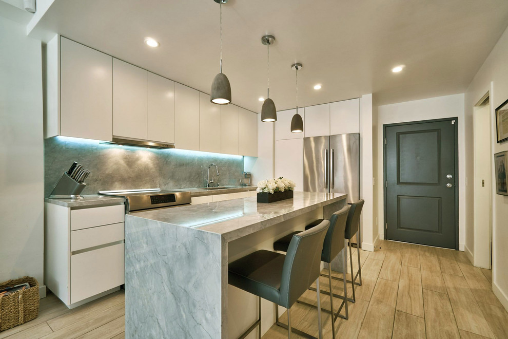 Design ideas for a small contemporary galley kitchen/diner in Los Angeles with a submerged sink, flat-panel cabinets, white cabinets, marble worktops, marble splashback, stainless steel appliances, porcelain flooring, an island, grey splashback and brown floors.