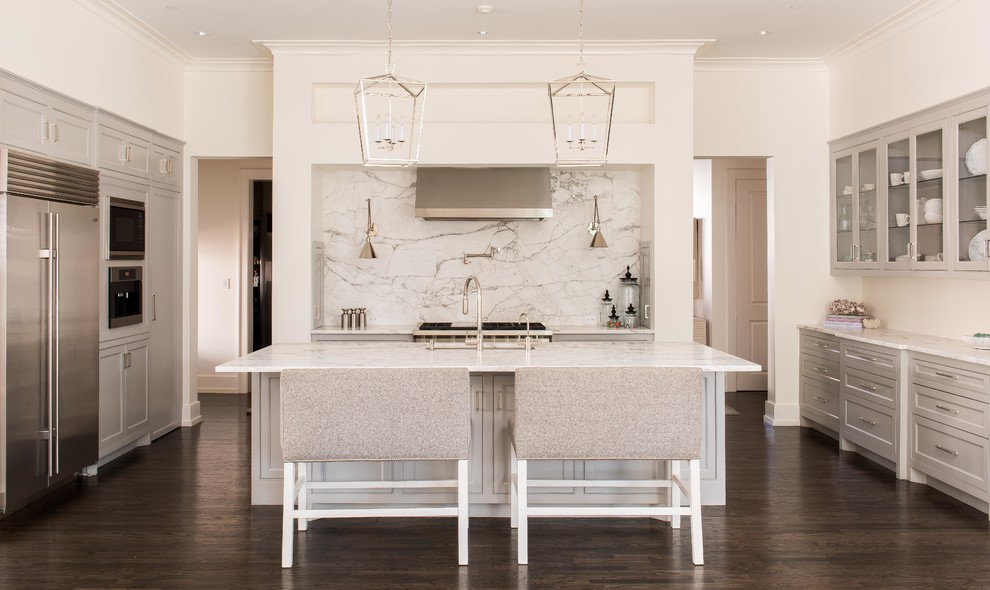 Example of a large transitional u-shaped dark wood floor and brown floor kitchen design in Dallas with recessed-panel cabinets, gray cabinets, marble countertops, stainless steel appliances, an island, an undermount sink, white backsplash and stone slab backsplash