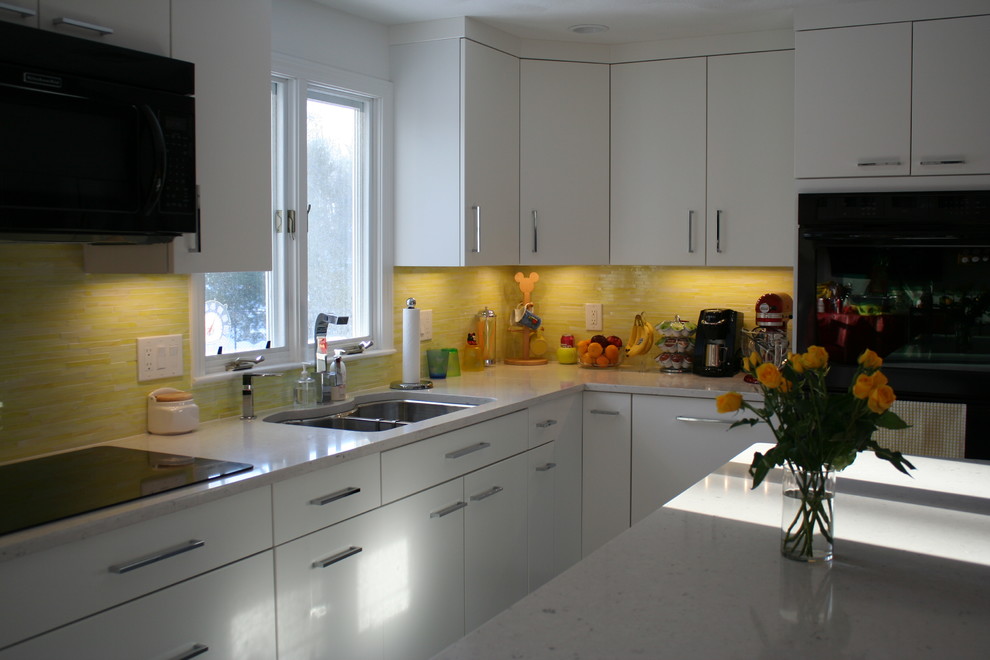 Photo of a medium sized contemporary l-shaped kitchen/diner in Boston with a submerged sink, flat-panel cabinets, grey cabinets, engineered stone countertops, yellow splashback, glass tiled splashback, stainless steel appliances, porcelain flooring and an island.