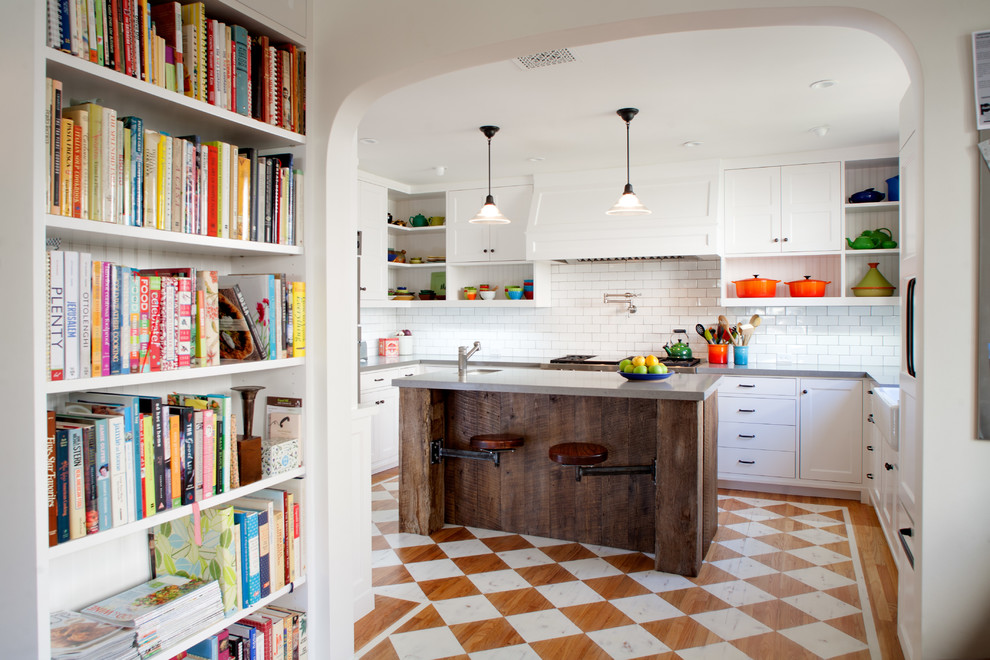 Urige Küche mit weißen Schränken, Küchenrückwand in Weiß, Rückwand aus Metrofliesen und gebeiztem Holzboden in Los Angeles
