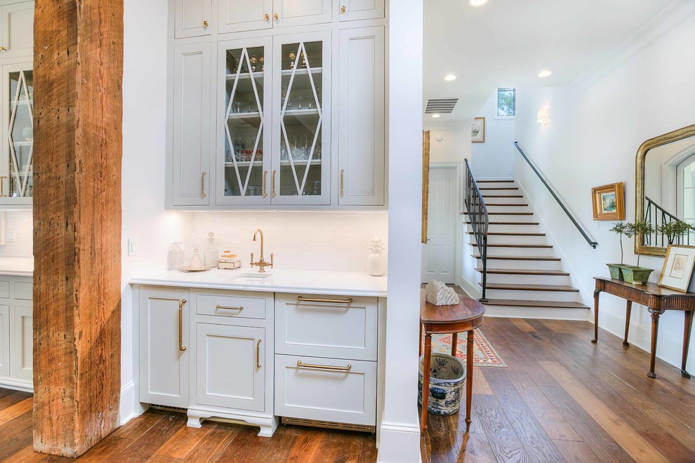 Exempel på ett mellanstort klassiskt vit linjärt vitt kök med öppen planlösning, med en undermonterad diskho, luckor med profilerade fronter, grå skåp, marmorbänkskiva, vitt stänkskydd, stänkskydd i keramik, integrerade vitvaror, mellanmörkt trägolv, en köksö och brunt golv