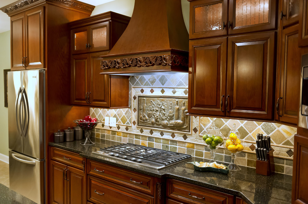 На фото: угловая кухня среднего размера в классическом стиле с фасадами с выступающей филенкой, темными деревянными фасадами, гранитной столешницей, разноцветным фартуком, фартуком из каменной плитки и техникой из нержавеющей стали