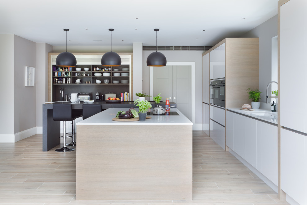 Photo of an expansive contemporary open plan kitchen in Surrey with an integrated sink, flat-panel cabinets, grey cabinets, quartz worktops, integrated appliances, porcelain flooring, an island, grey floors and white worktops.