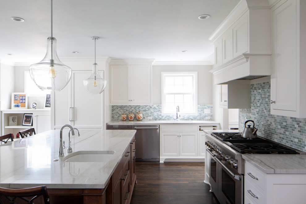 Bild på ett mellanstort vintage vit vitt kök, med en undermonterad diskho, skåp i shakerstil, bruna skåp, bänkskiva i kvarts, grönt stänkskydd, stänkskydd i glaskakel, rostfria vitvaror, mörkt trägolv, en köksö och brunt golv