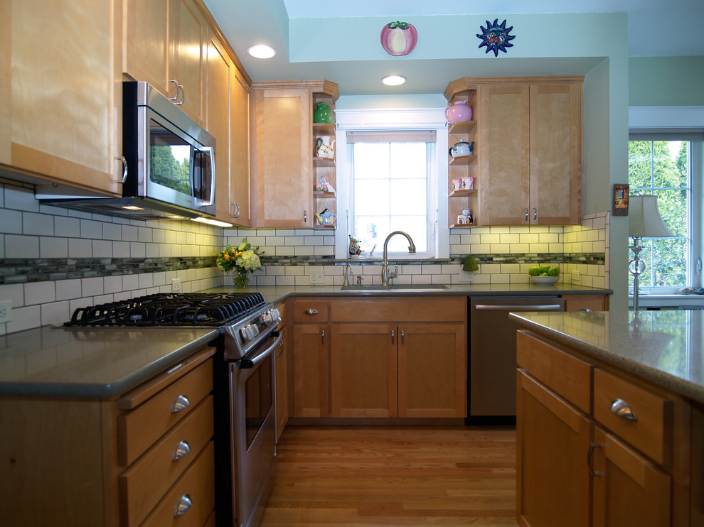 シアトルにある小さなトランジショナルスタイルのおしゃれなキッチン (アンダーカウンターシンク、シェーカースタイル扉のキャビネット、淡色木目調キャビネット、クオーツストーンカウンター、緑のキッチンパネル、ガラスタイルのキッチンパネル、シルバーの調理設備、淡色無垢フローリング、ベージュの床、緑のキッチンカウンター) の写真