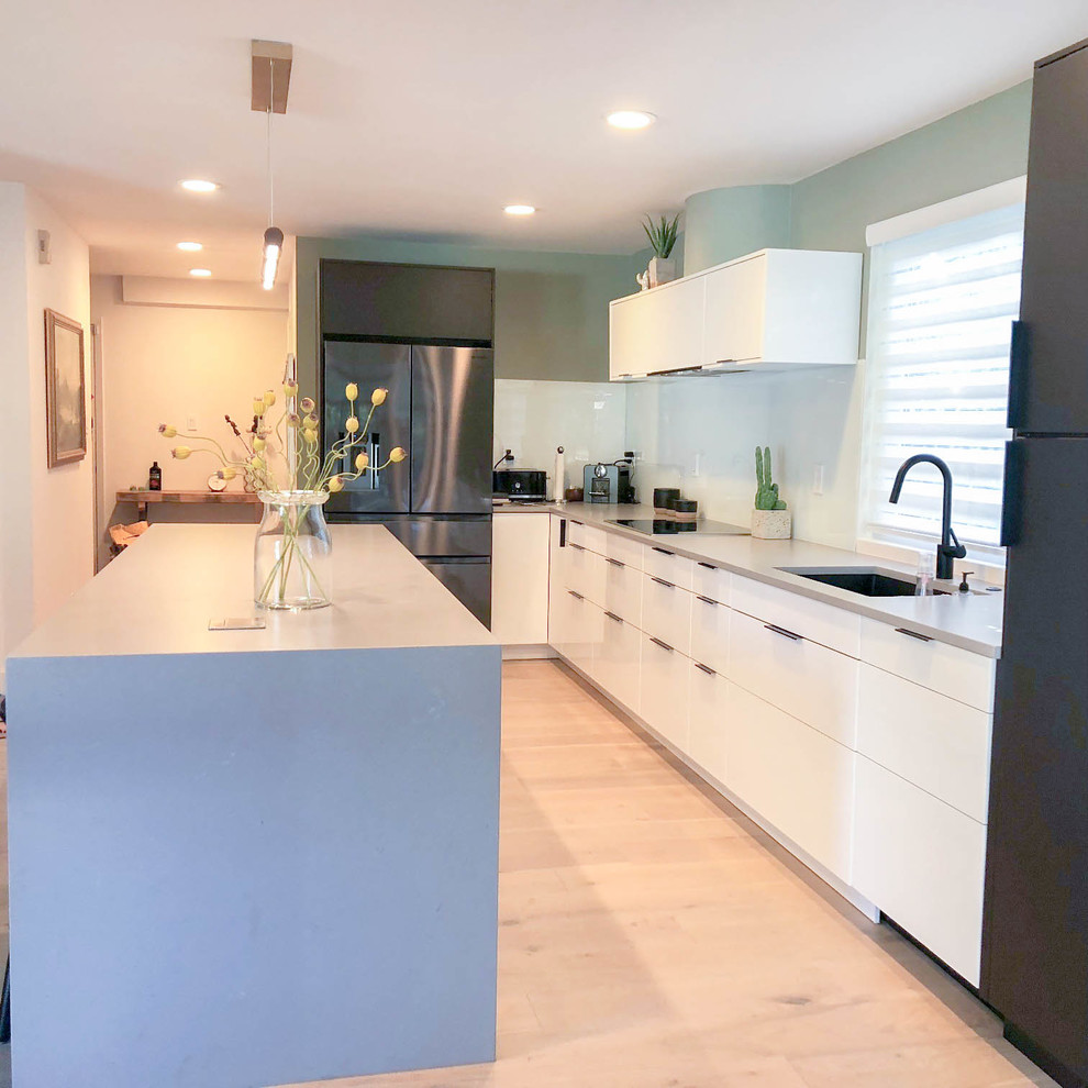 Exempel på ett stort modernt grå grått kök, med en undermonterad diskho, släta luckor, svarta skåp, bänkskiva i kvartsit, vitt stänkskydd, svarta vitvaror, mellanmörkt trägolv, en köksö och brunt golv
