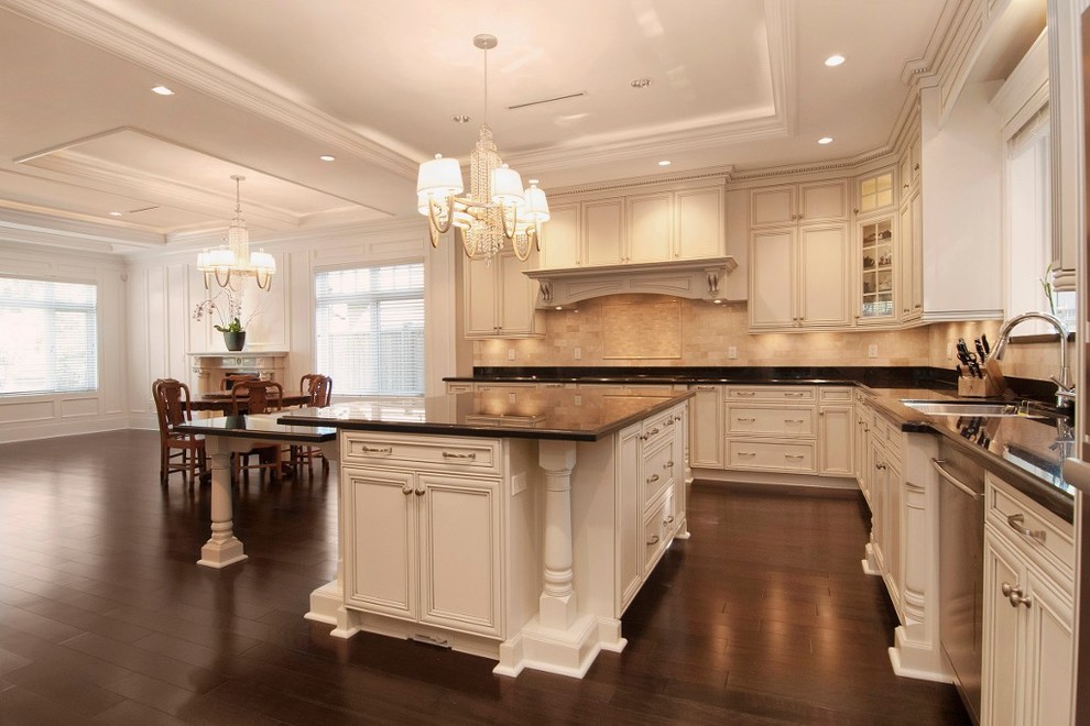 Eat-in kitchen - traditional u-shaped eat-in kitchen idea in Vancouver with an undermount sink, raised-panel cabinets, white cabinets, granite countertops, beige backsplash and stainless steel appliances