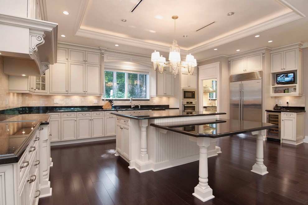 Elegant u-shaped eat-in kitchen photo in Vancouver with an undermount sink, raised-panel cabinets, white cabinets, granite countertops, beige backsplash and stainless steel appliances