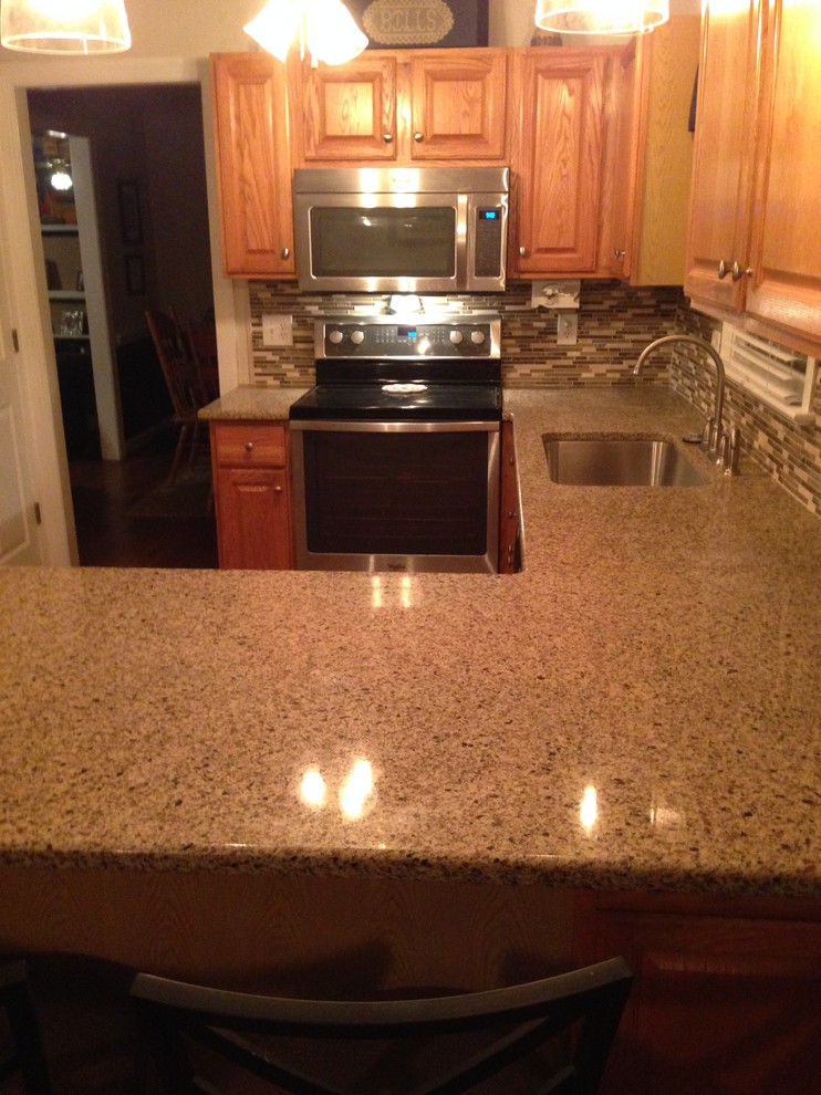 Foto di una cucina ad U tradizionale con lavello sottopiano, ante in legno scuro, top in granito e elettrodomestici in acciaio inossidabile
