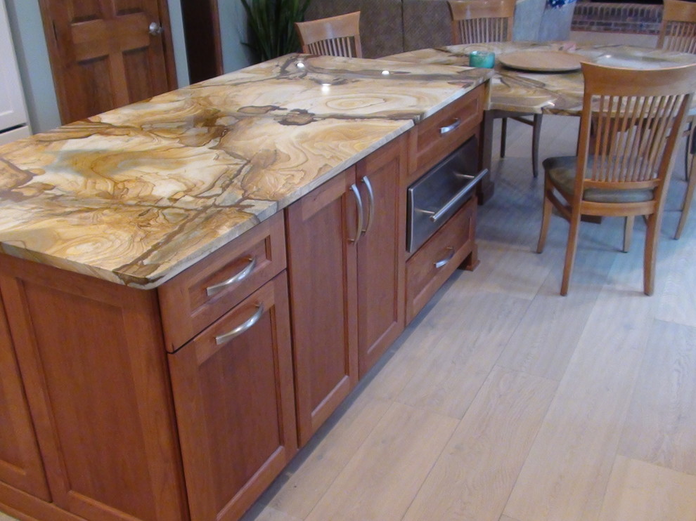 Large contemporary u-shaped kitchen/diner in Chicago with a submerged sink, recessed-panel cabinets, white cabinets, glass tiled splashback, stainless steel appliances, light hardwood flooring and an island.