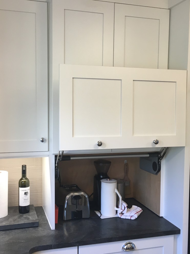 Photo of a small rural u-shaped open plan kitchen in Other with a belfast sink, shaker cabinets, white cabinets, soapstone worktops, grey splashback, ceramic splashback, stainless steel appliances, dark hardwood flooring, an island and brown floors.
