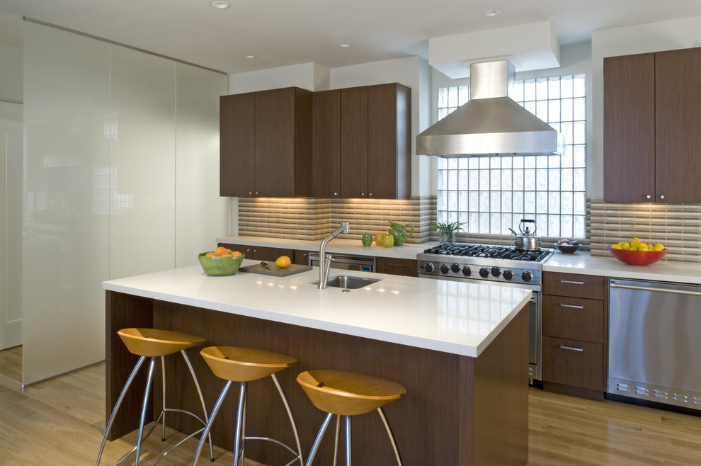 Imagen de cocina actual con electrodomésticos de acero inoxidable, armarios con paneles lisos, puertas de armario de madera en tonos medios y salpicadero multicolor