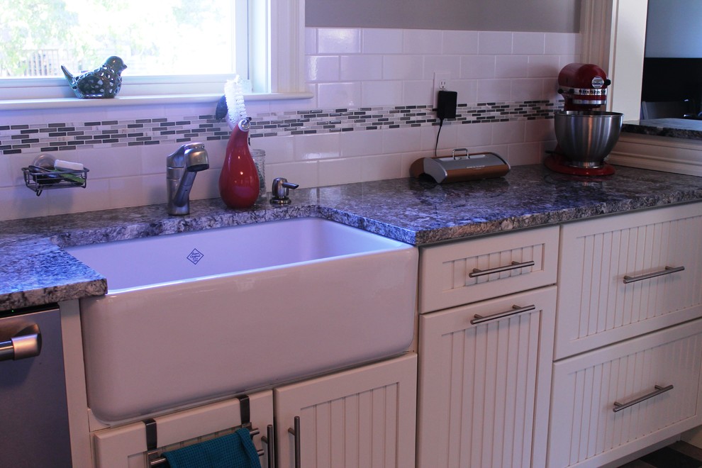 Immagine di una cucina classica con lavello stile country, ante bianche, top in granito, paraspruzzi bianco e elettrodomestici in acciaio inossidabile