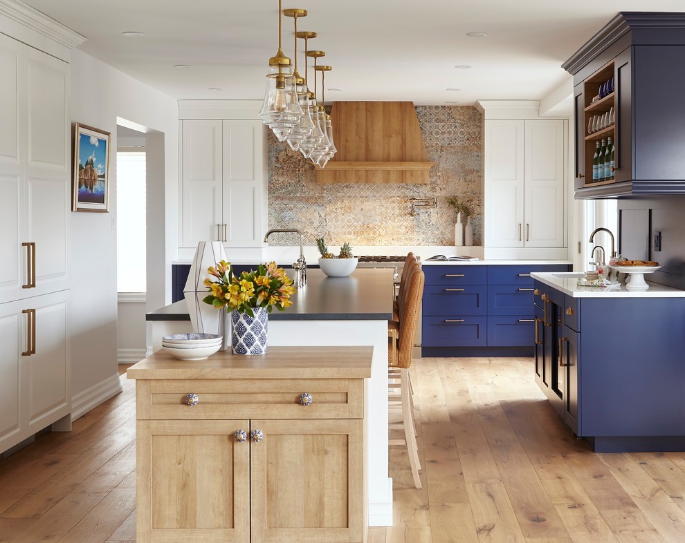 Bild på ett mycket stort vintage blå blått kök, med en undermonterad diskho, skåp i shakerstil, blå skåp, bänkskiva i kvarts, integrerade vitvaror, ljust trägolv, en köksö och brunt golv