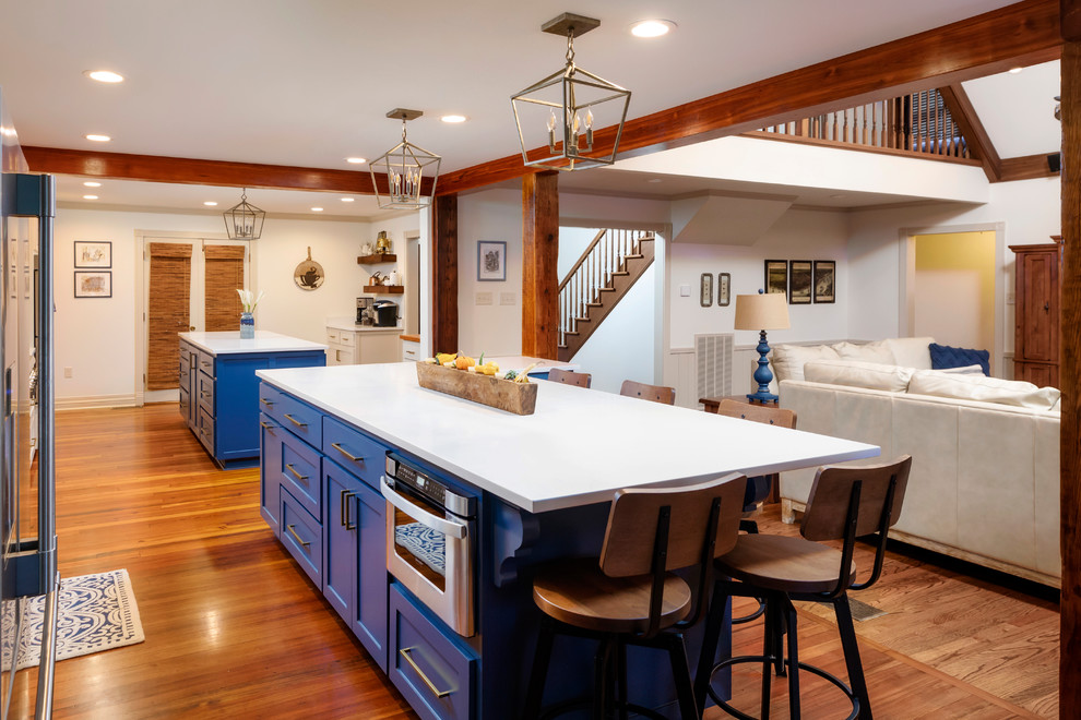 Idéer för ett stort klassiskt vit kök med öppen planlösning, med luckor med infälld panel, blå skåp, rostfria vitvaror, flera köksöar, brunt golv och mellanmörkt trägolv