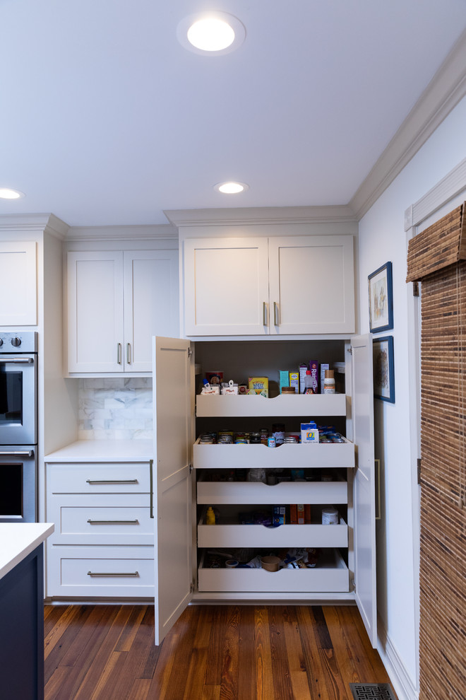 Inredning av ett stort vit vitt kök med öppen planlösning, med luckor med infälld panel, blå skåp, rostfria vitvaror, ljust trägolv, flera köksöar och brunt golv
