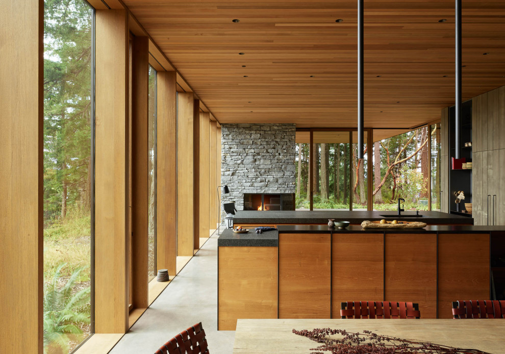 Cette image montre une grande cuisine parallèle minimaliste avec un placard à porte plane, un plan de travail en granite, sol en béton ciré, 2 îlots, plan de travail noir et un plafond en bois.