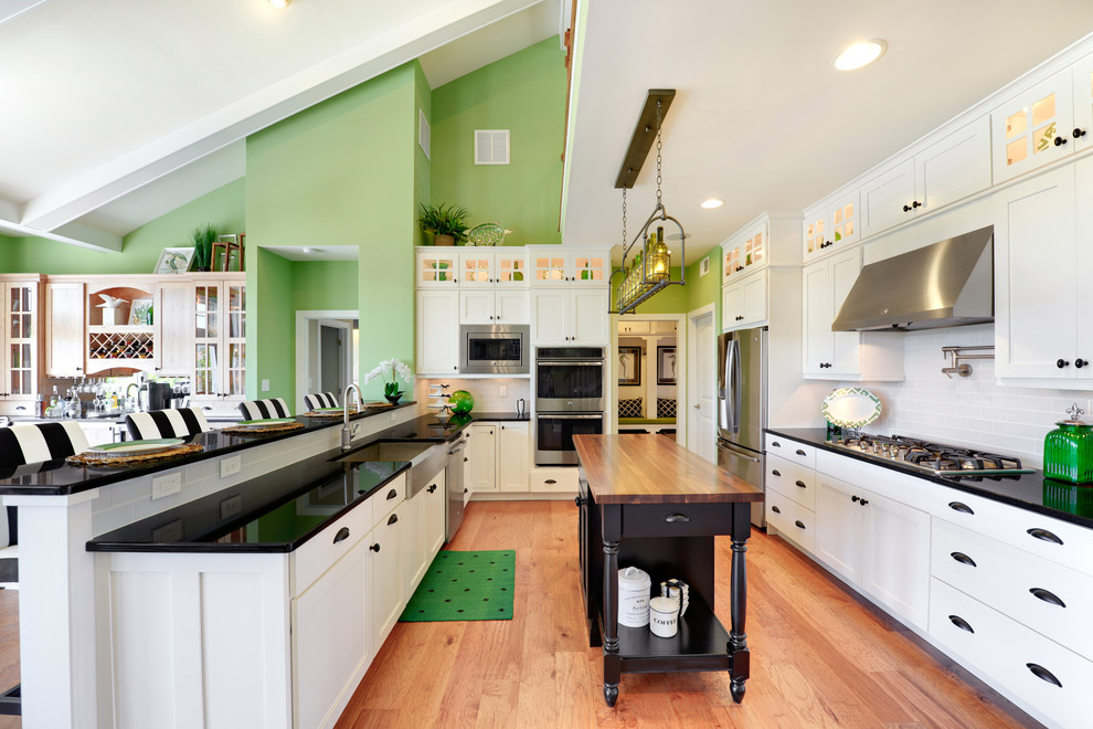 Inspiration for a large coastal u-shaped open concept kitchen remodel in Philadelphia with a farmhouse sink, recessed-panel cabinets, white cabinets, white backsplash, subway tile backsplash and two islands