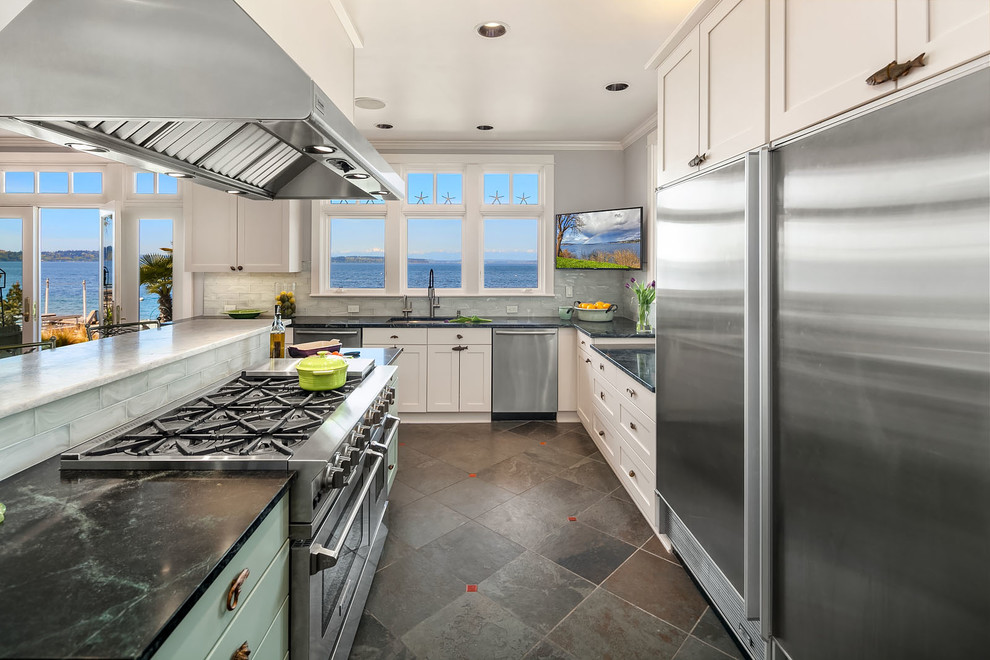 Example of a large beach style slate floor and green floor open concept kitchen design in Seattle with an undermount sink, shaker cabinets, soapstone countertops, glass tile backsplash, stainless steel appliances, an island and green countertops