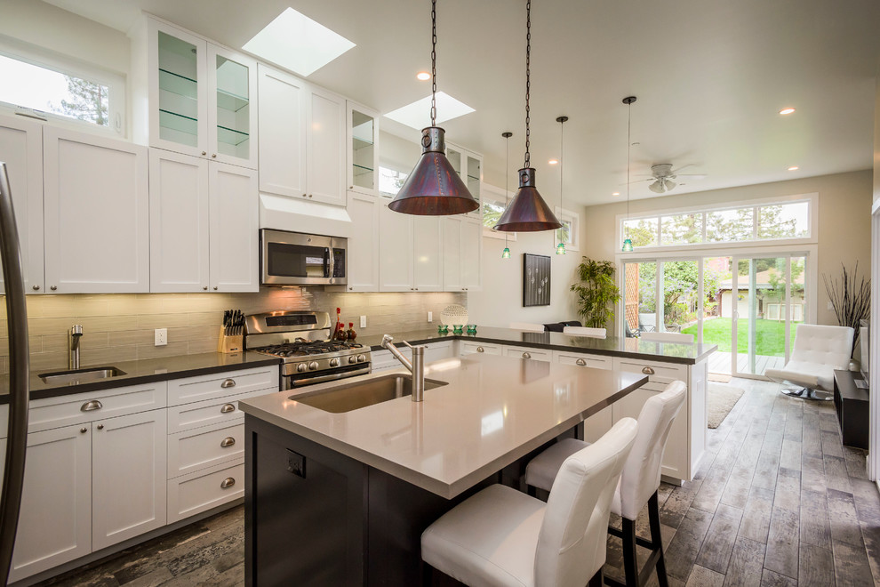 Inspiration for a large contemporary l-shaped open concept kitchen remodel in San Francisco with an undermount sink, recessed-panel cabinets, white cabinets, wood countertops, gray backsplash, stainless steel appliances and an island