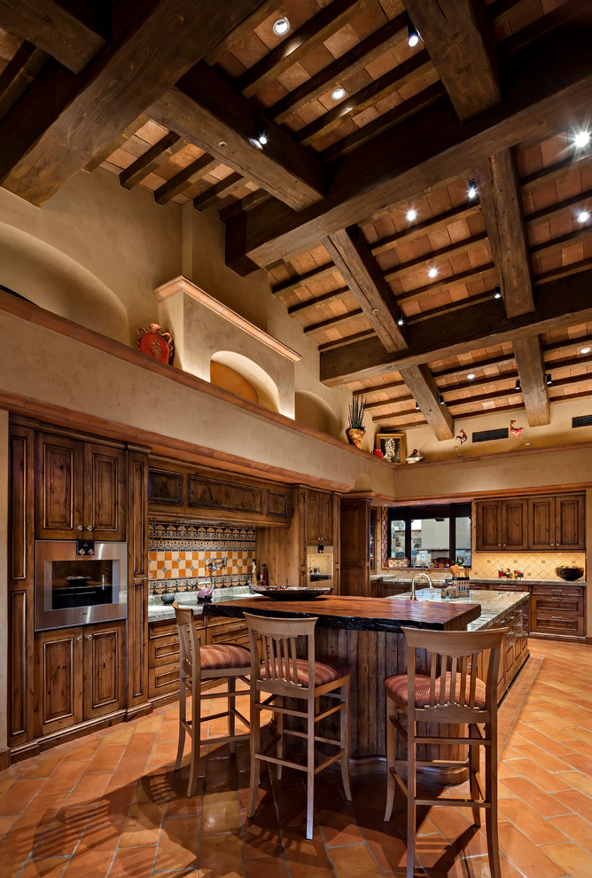 Mediterrane Küche mit Rückwand aus Zementfliesen, Kücheninsel, dunklen Holzschränken, bunter Rückwand, Terrakottaboden und orangem Boden in Phoenix