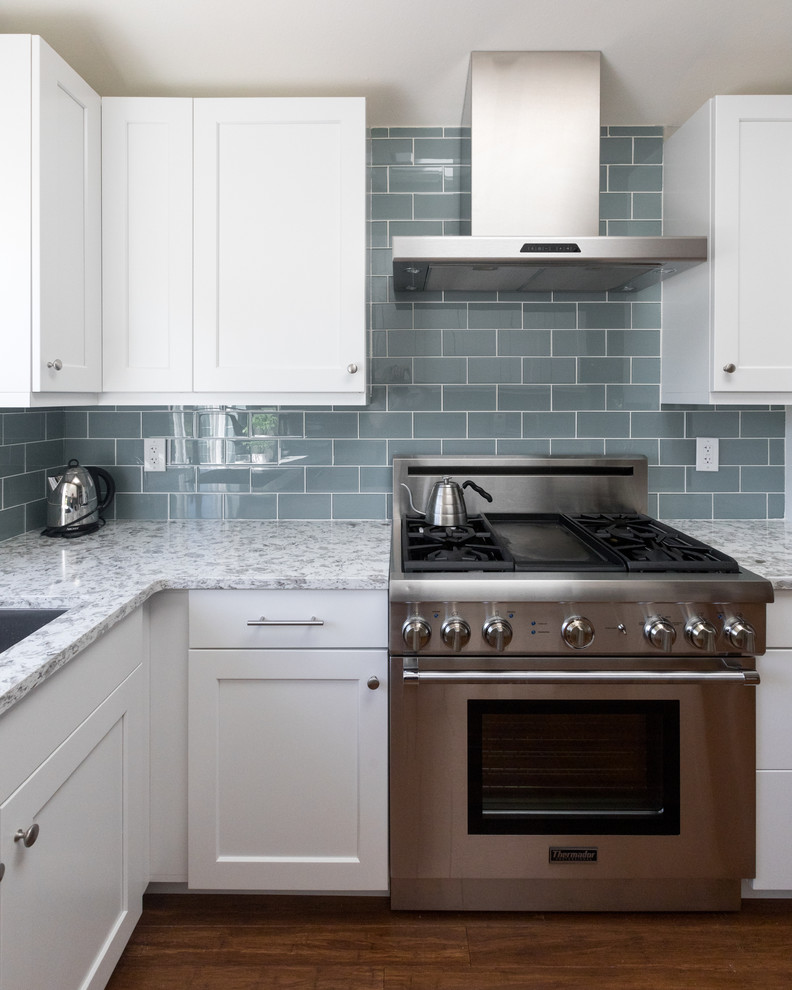Idéer för ett mellanstort modernt flerfärgad kök, med en undermonterad diskho, skåp i shakerstil, vita skåp, bänkskiva i kvarts, blått stänkskydd, stänkskydd i glaskakel, rostfria vitvaror, mellanmörkt trägolv och flerfärgat golv