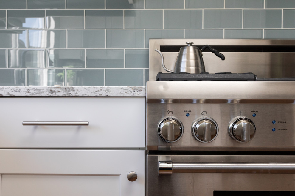 Foto på ett mellanstort funkis flerfärgad kök, med en undermonterad diskho, skåp i shakerstil, vita skåp, bänkskiva i kvarts, blått stänkskydd, stänkskydd i glaskakel, rostfria vitvaror, mellanmörkt trägolv och flerfärgat golv