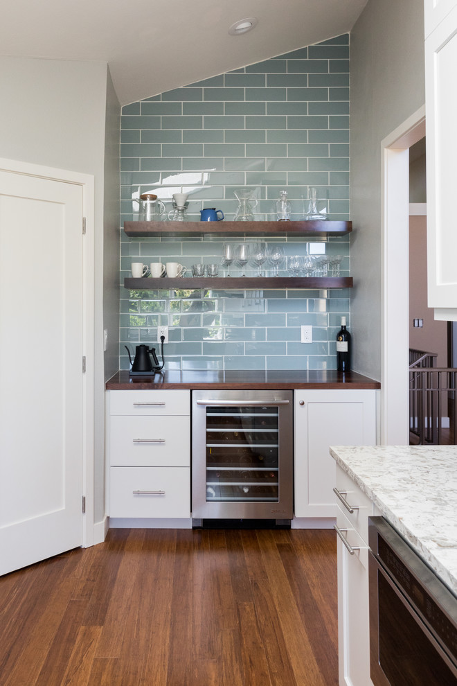 Modern inredning av ett mellanstort flerfärgad flerfärgat kök, med en undermonterad diskho, skåp i shakerstil, vita skåp, bänkskiva i kvarts, blått stänkskydd, stänkskydd i glaskakel, rostfria vitvaror, mellanmörkt trägolv och flerfärgat golv