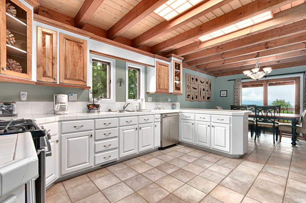 Example of a large minimalist porcelain tile kitchen design in Other with a double-bowl sink, glass-front cabinets, white cabinets, tile countertops, white backsplash, ceramic backsplash and stainless steel appliances