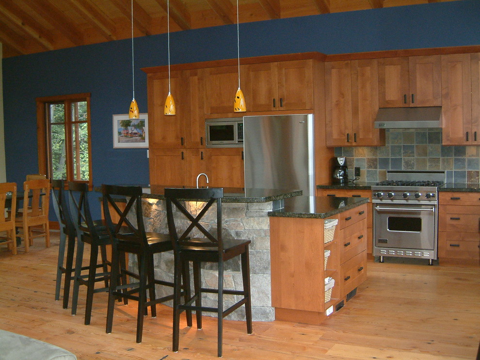 На фото: угловая кухня в классическом стиле с обеденным столом, врезной мойкой, фасадами в стиле шейкер, фасадами цвета дерева среднего тона, гранитной столешницей, синим фартуком, фартуком из каменной плитки и техникой из нержавеющей стали