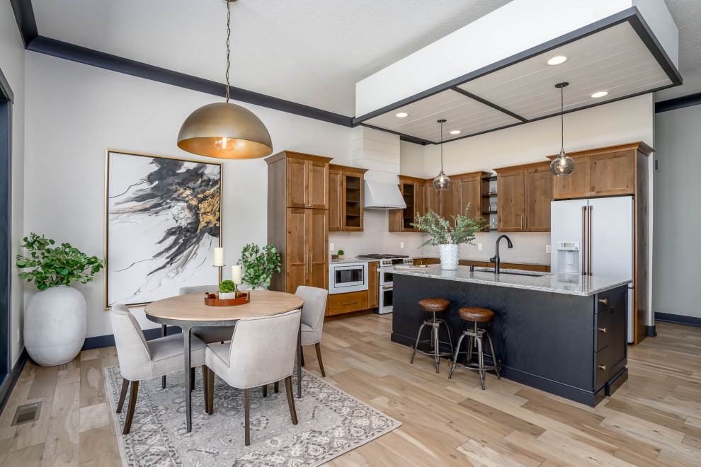 Transitional l-shaped light wood floor and beige floor kitchen photo in Chicago with an undermount sink, shaker cabinets, medium tone wood cabinets, gray backsplash, white appliances, an island and gray countertops