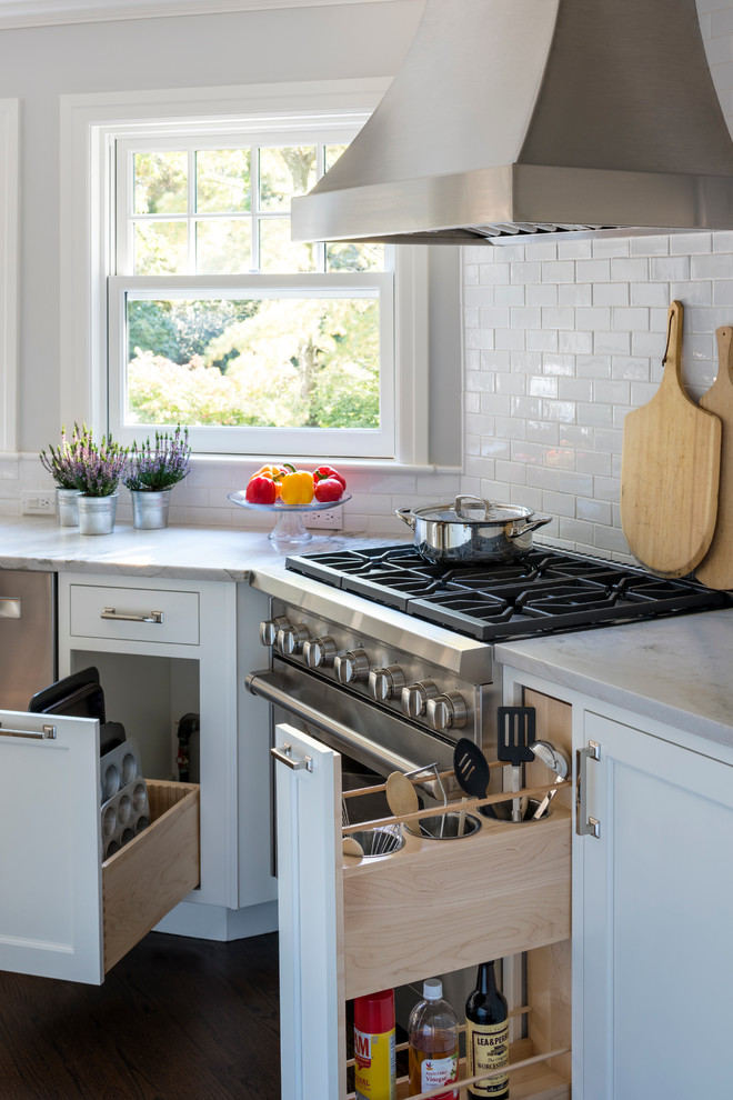 Inspiration for a mid-sized transitional l-shaped dark wood floor eat-in kitchen remodel in New York with an undermount sink, shaker cabinets, white cabinets, quartzite countertops, white backsplash, ceramic backsplash, stainless steel appliances and an island