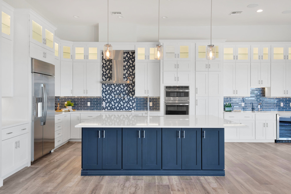 Large minimalist l-shaped medium tone wood floor and brown floor eat-in kitchen photo in Phoenix with an undermount sink, shaker cabinets, white cabinets, quartz countertops, blue backsplash, ceramic backsplash, stainless steel appliances, an island and white countertops