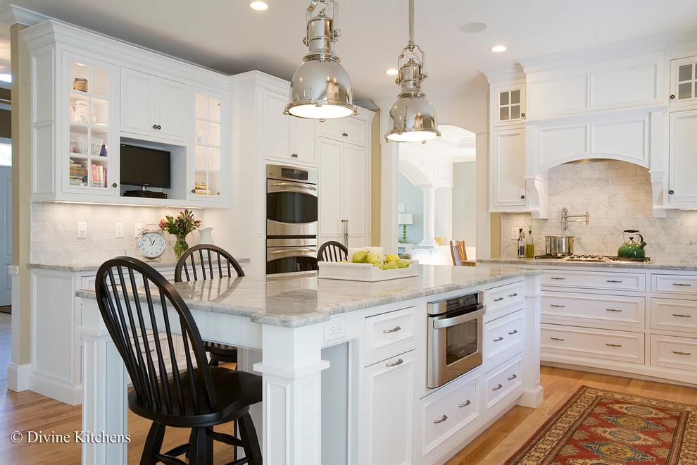 Inspiration for a large timeless galley light wood floor eat-in kitchen remodel in Boston with a farmhouse sink, beaded inset cabinets, granite countertops, white backsplash, stainless steel appliances, an island and white cabinets