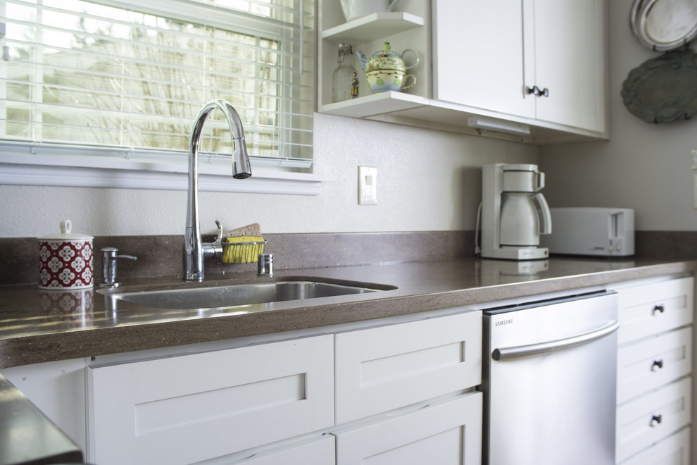 Example of a mid-sized trendy l-shaped medium tone wood floor eat-in kitchen design in Seattle with an undermount sink, shaker cabinets, white cabinets, solid surface countertops, brown backsplash and stainless steel appliances