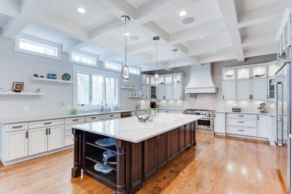Large traditional u-shaped kitchen in DC Metro with a submerged sink, recessed-panel cabinets, engineered stone countertops, stainless steel appliances, medium hardwood flooring and an island.