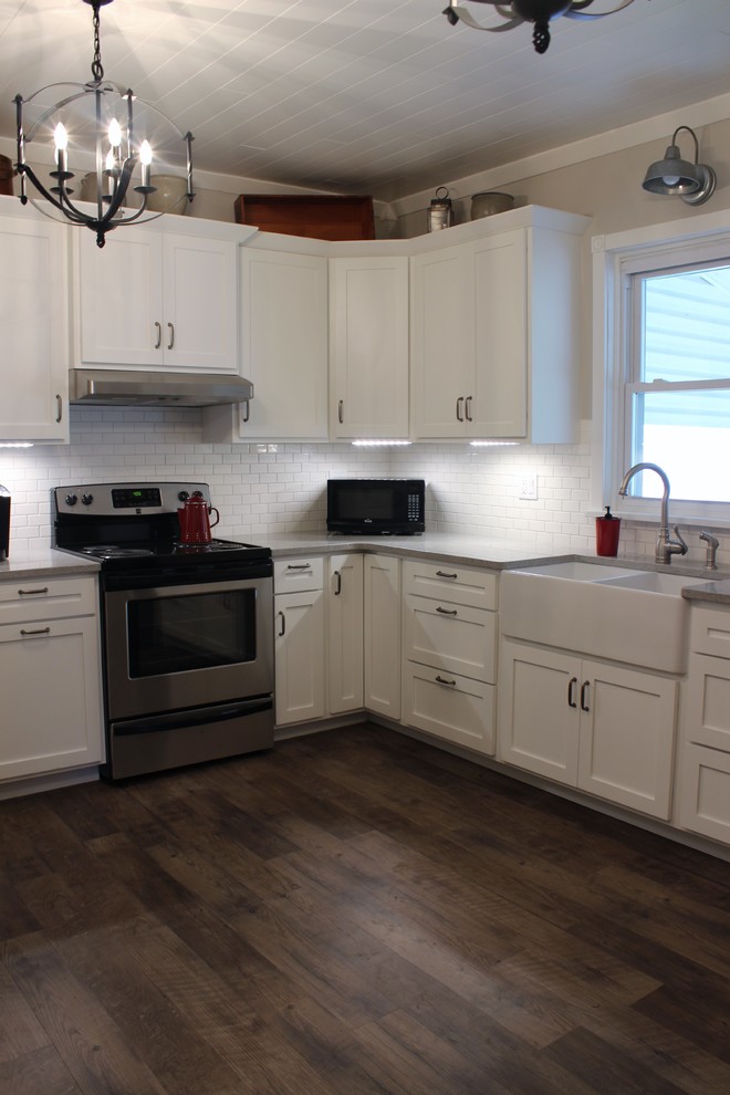 Bild på ett avskilt, mellanstort lantligt l-kök, med en rustik diskho, skåp i shakerstil, vita skåp, bänkskiva i kvarts, vitt stänkskydd, stänkskydd i tunnelbanekakel, rostfria vitvaror och linoleumgolv