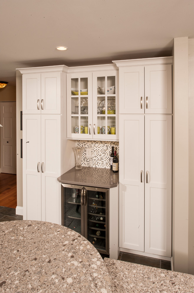 Example of a mid-sized transitional l-shaped porcelain tile eat-in kitchen design in Philadelphia with an undermount sink, shaker cabinets, white cabinets, quartz countertops, white backsplash, stone tile backsplash, stainless steel appliances and an island
