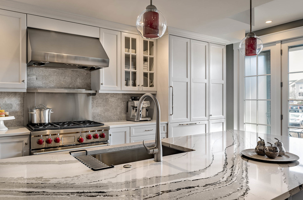 Design ideas for a large traditional galley kitchen/diner in Boston with a submerged sink, shaker cabinets, white cabinets, engineered stone countertops, grey splashback, stainless steel appliances, medium hardwood flooring and an island.