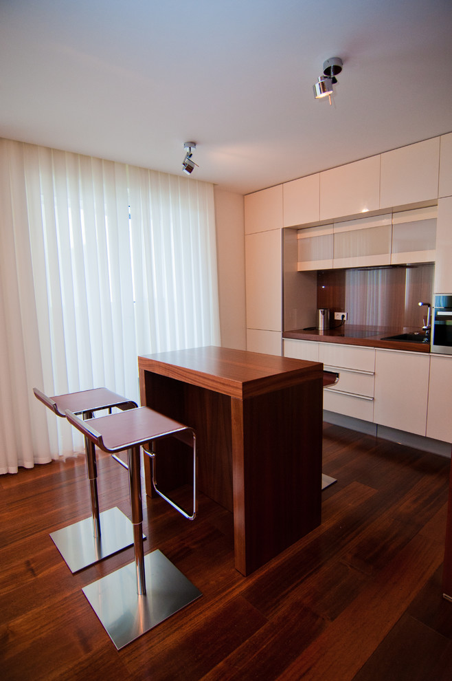 Zweizeilige, Mittelgroße Moderne Wohnküche mit Waschbecken, Arbeitsplatte aus Holz und gebeiztem Holzboden in Sankt Petersburg